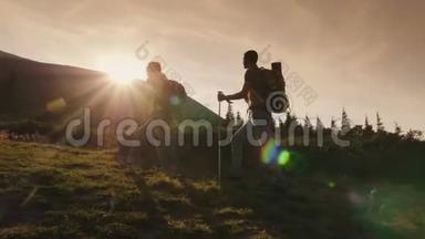 两个旅行者爬上一座山。 落日<strong>余晖</strong>中的剪影。